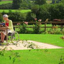 Woman in a wheelchair in the garden, reading
