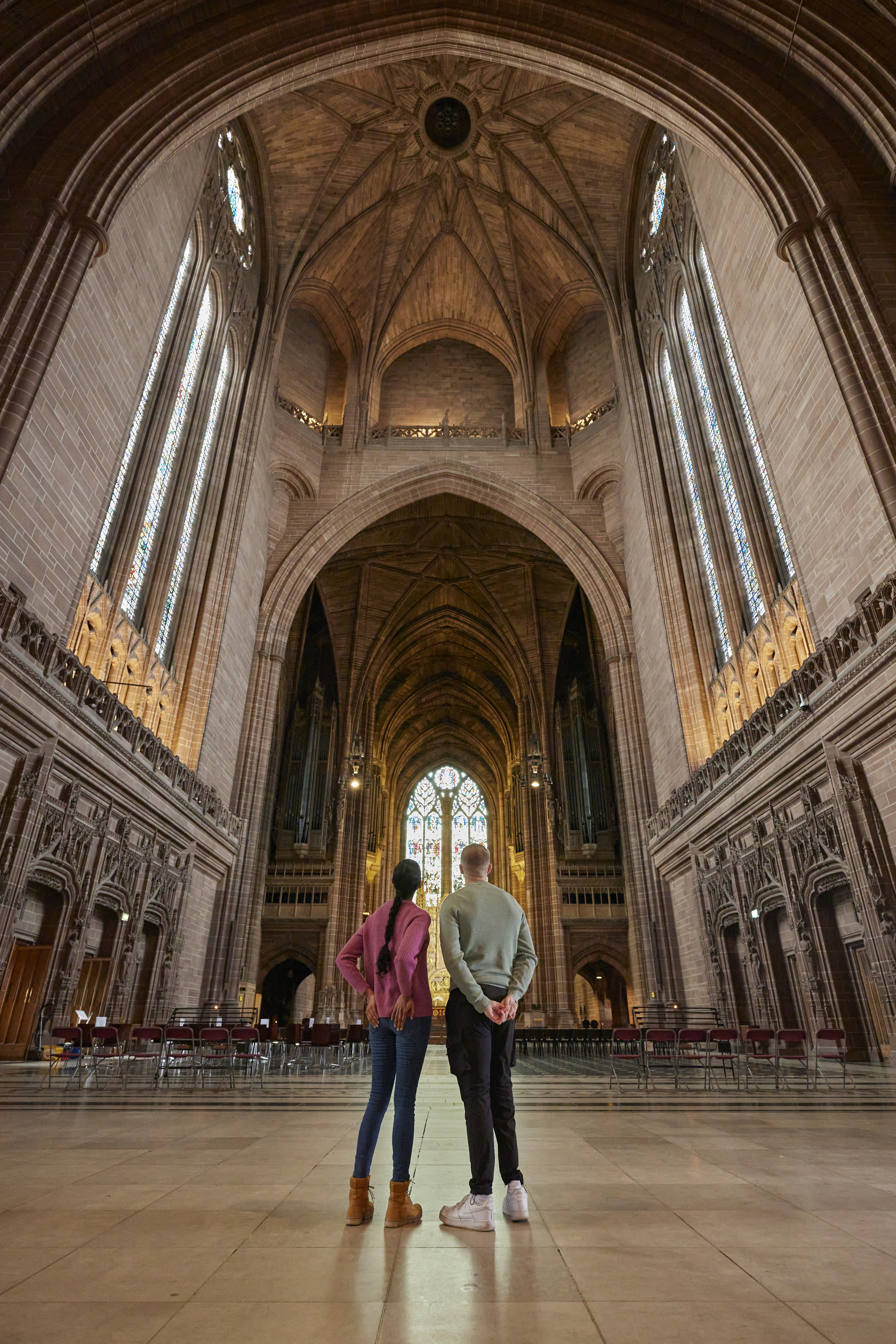 Two people take a tour of an Anglican Cathedral.
