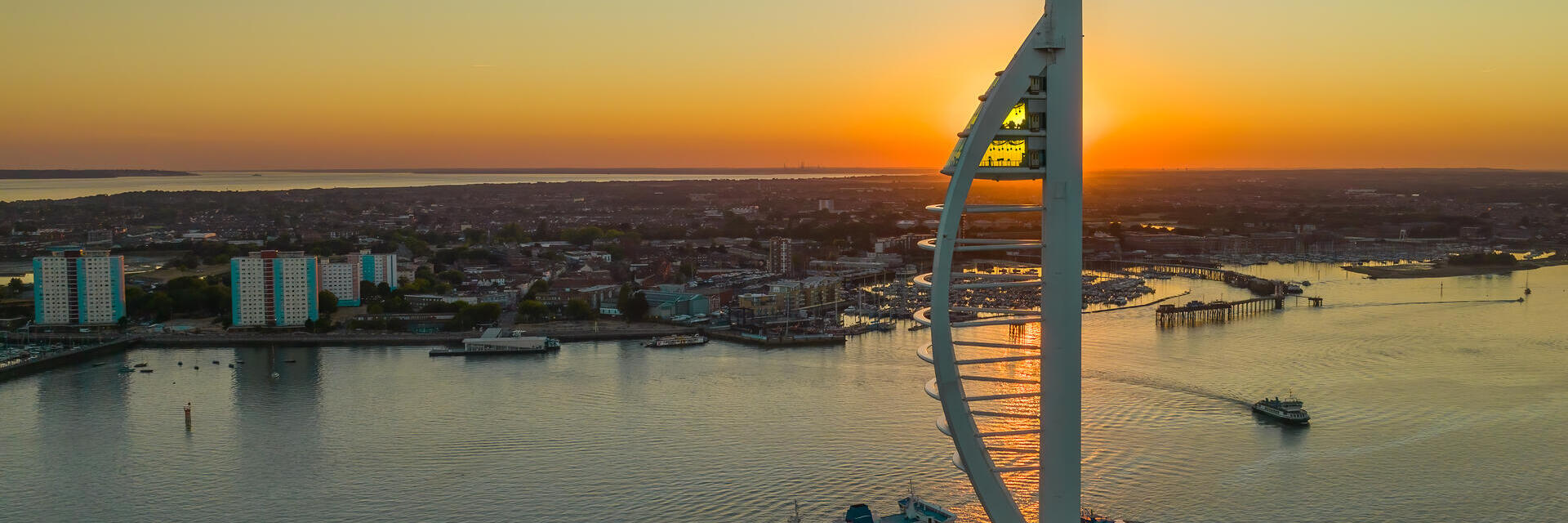 A modern tower next to the ocean at sunset