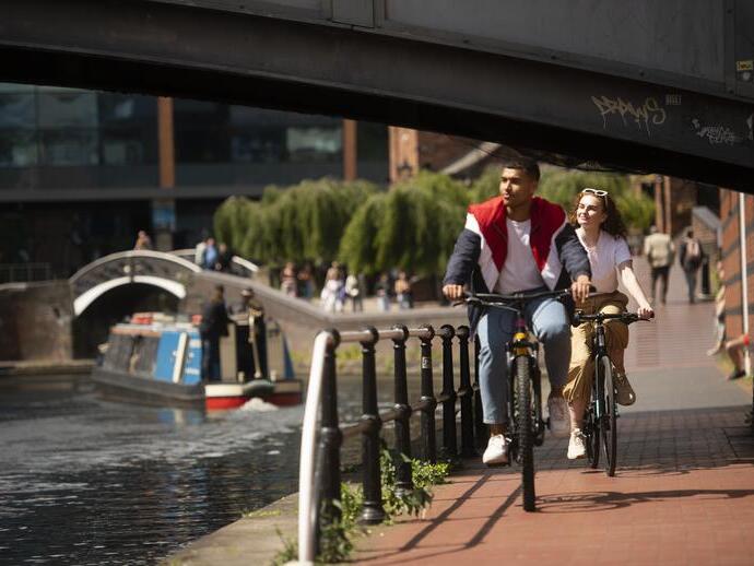 Ein Paar fährt mit dem Fahrrad eine Rampe parallel zu einem Kanal hinunter