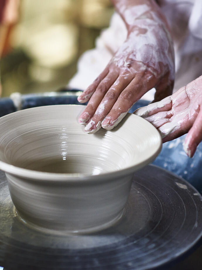Donna che realizza una ciotola di ceramica al tornio.