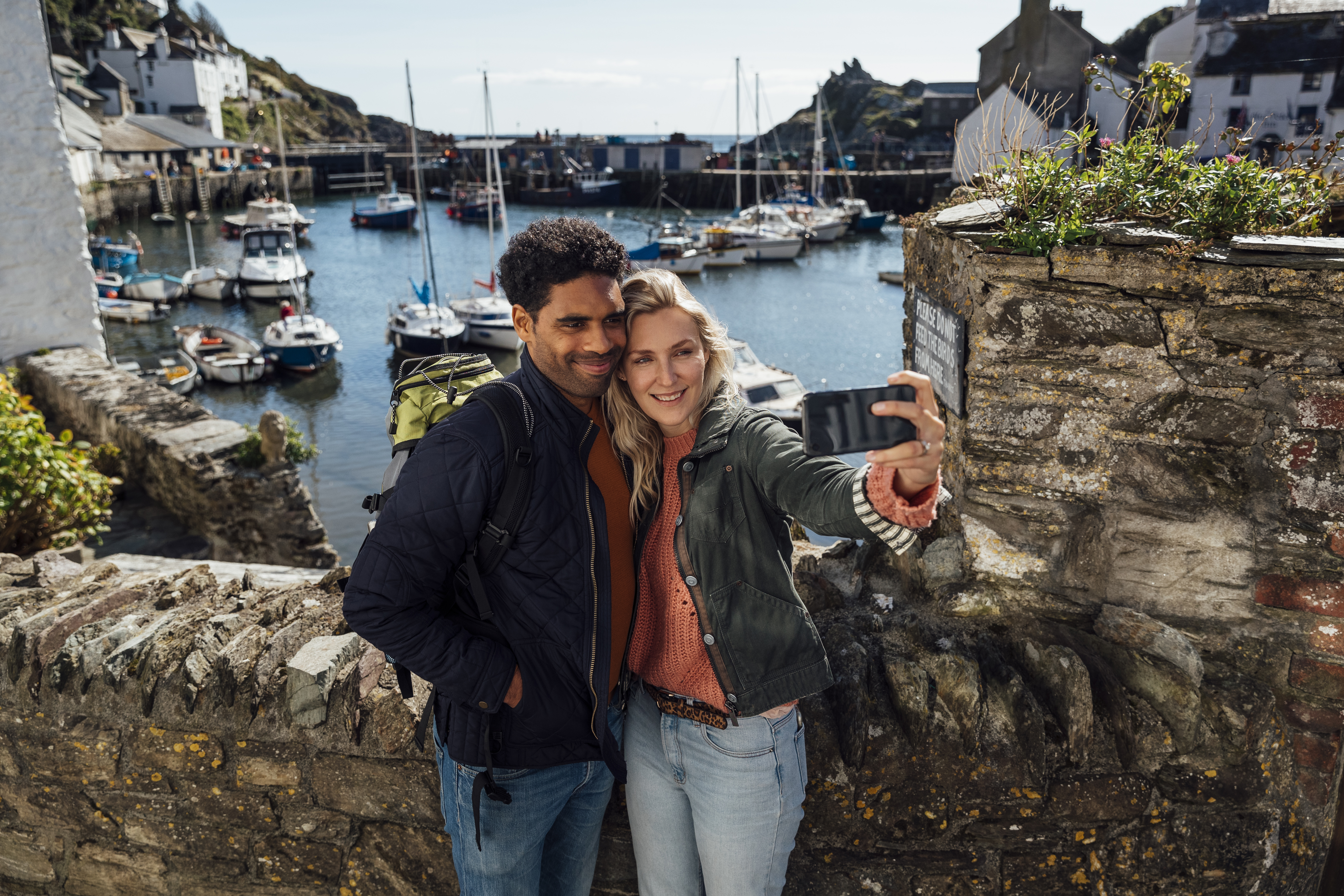 A couple taking a selfie using a smart phone while on holiday in Polperro, Cornwall.