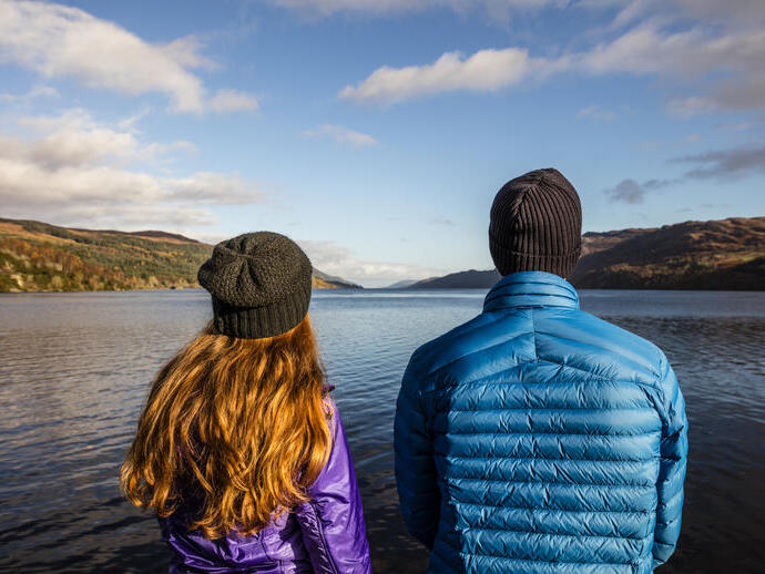 Couple contemplant les eaux calmes d'un lac entouré de collines