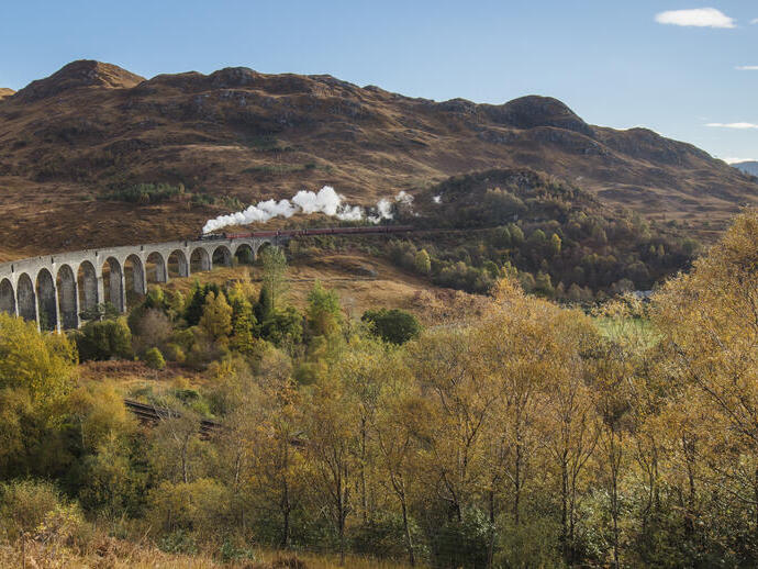 Eine Dampflokomotive auf dem Glenfinnan-Viadukt, einem historischen Viadukt, das das Tal bei Glenfinnan überquert.