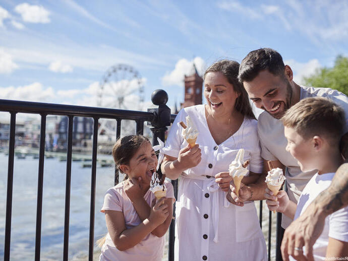 Family eating ice cream in a bay with a Ferris wheel behind
