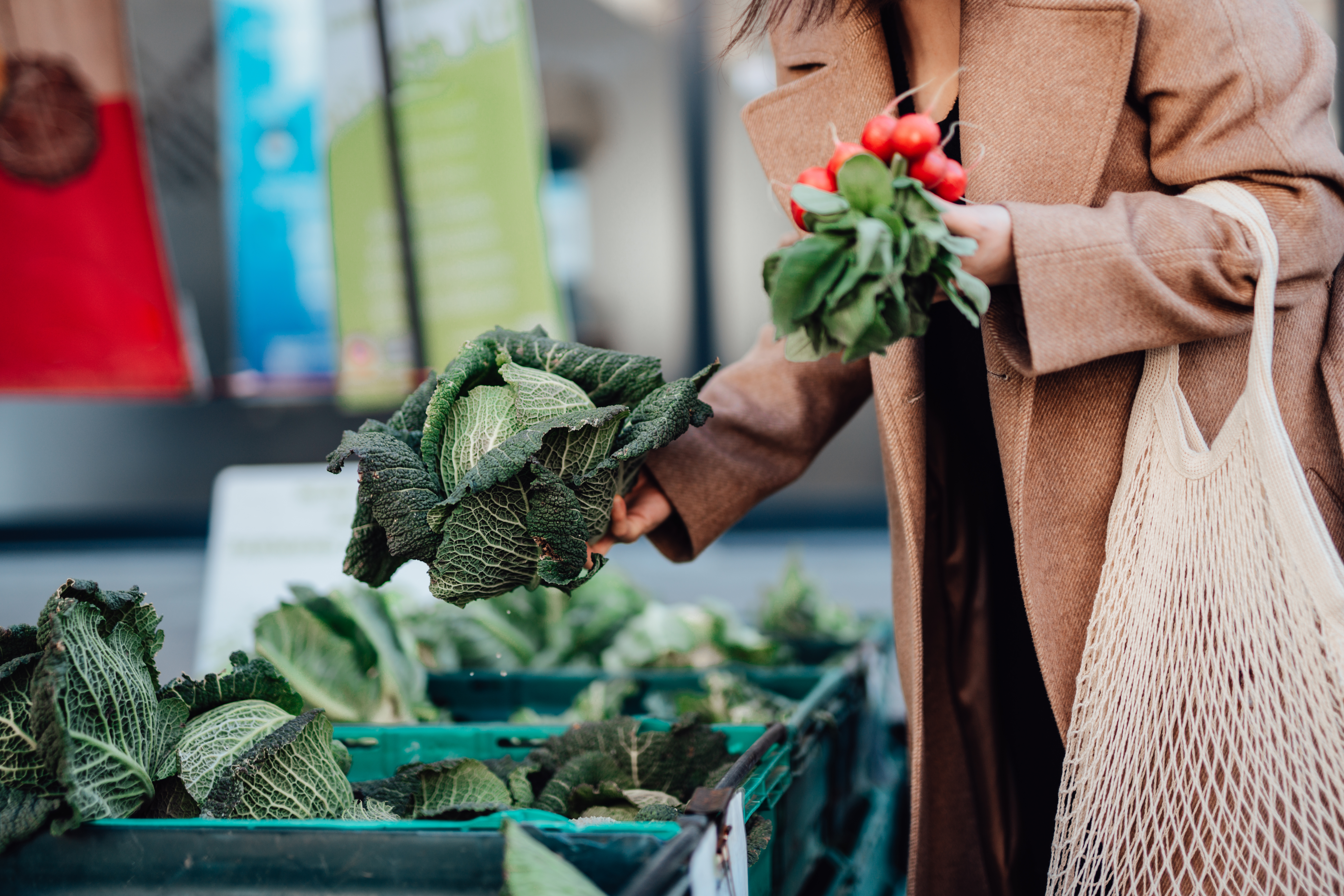 Una mujer comprando verduras ecológicas frescas en un mercado agrícola.