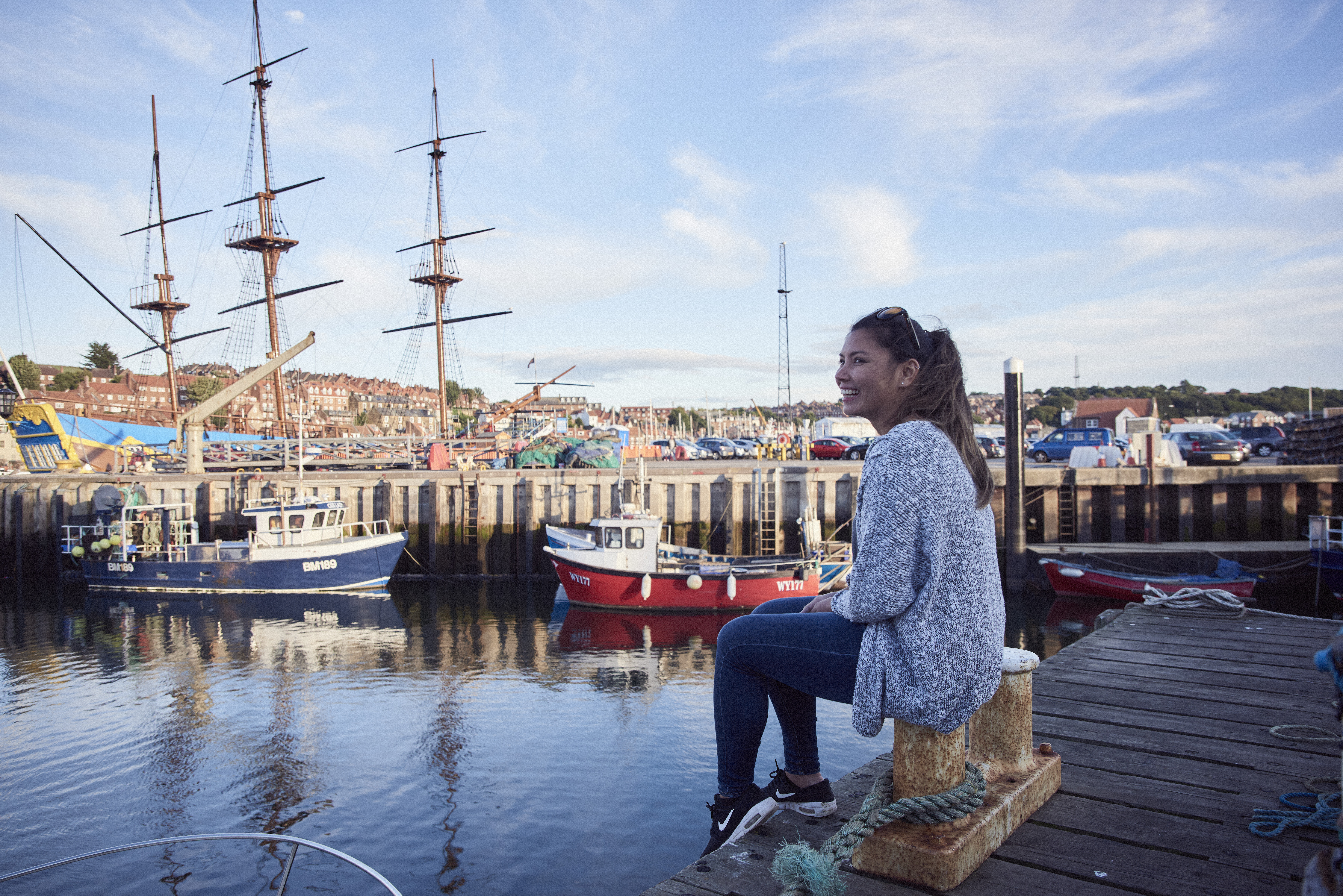 Smiling woman sitting on a jetty in a harbour