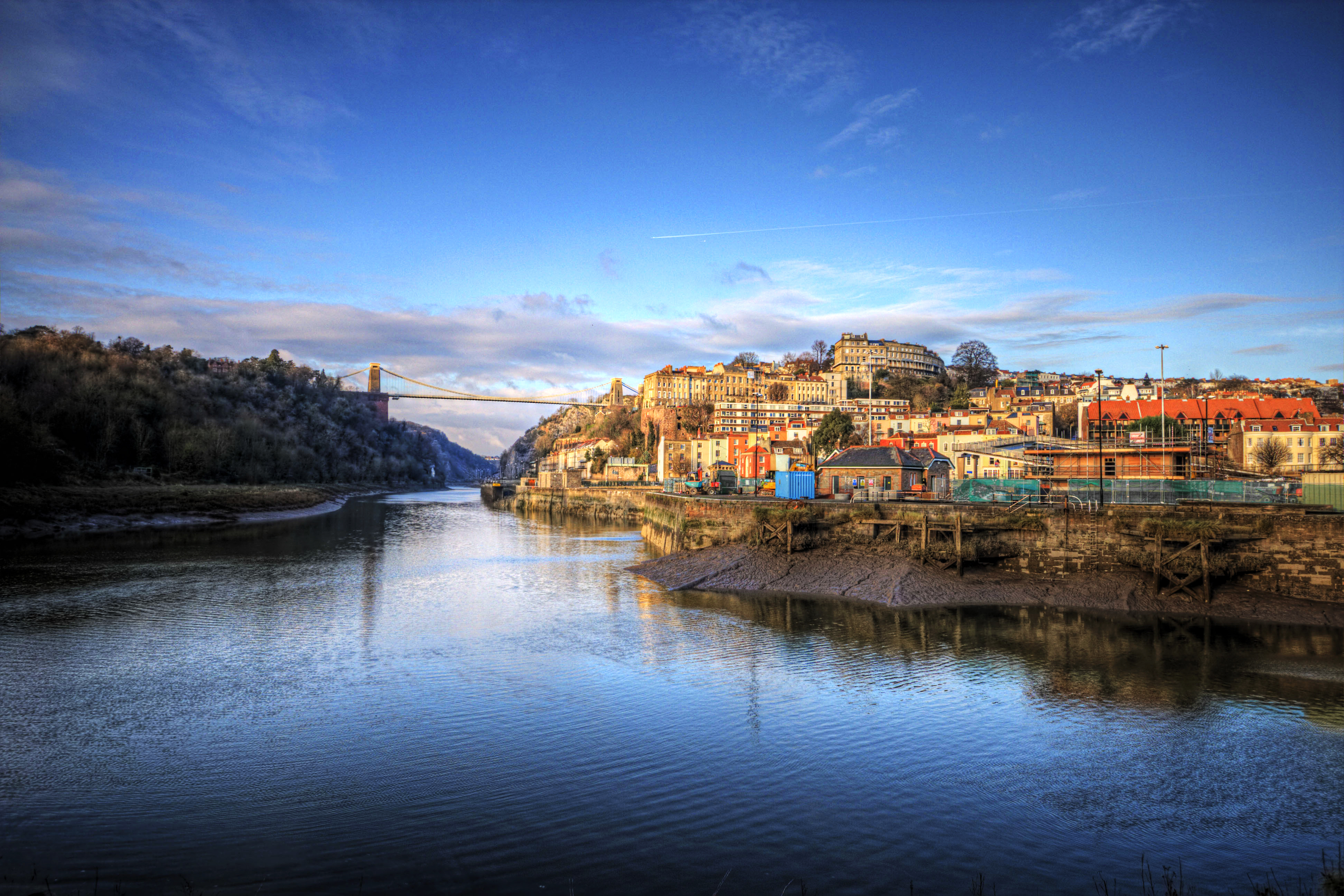 Una ciudad a orillas de un río con un gran puente en la distancia.