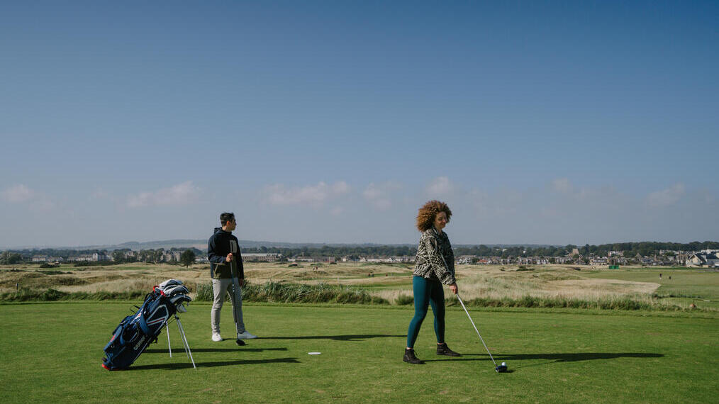 A man and a woman playing golf at a country golf club.