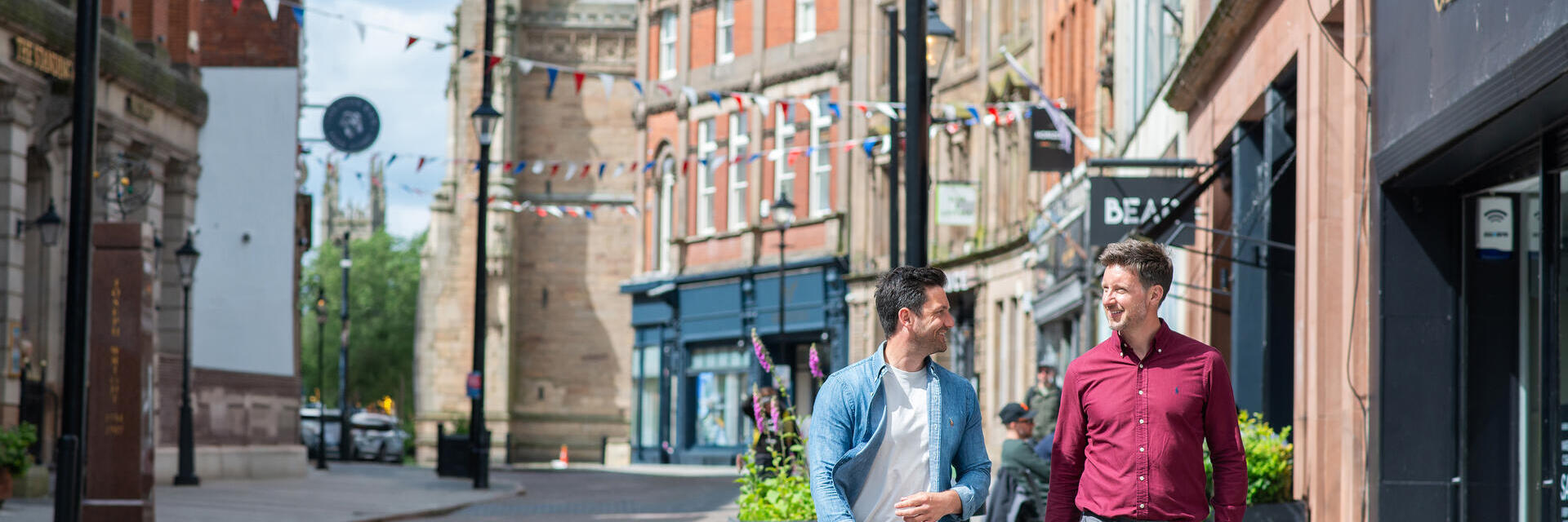 Due uomini camminano davanti a negozi e ristoranti