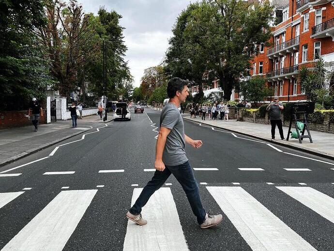 A man crossing the road outside of Abbey Road Studios, a recreation of the famous album cover from The Beatles
