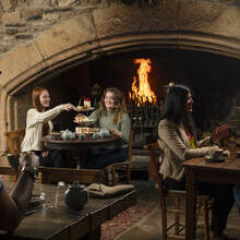 Two women enjoy an Afternoon Tea in front of a fire in an traditional historic pub