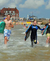 Niños con tablas de surf corriendo hacia el mar en Norwich