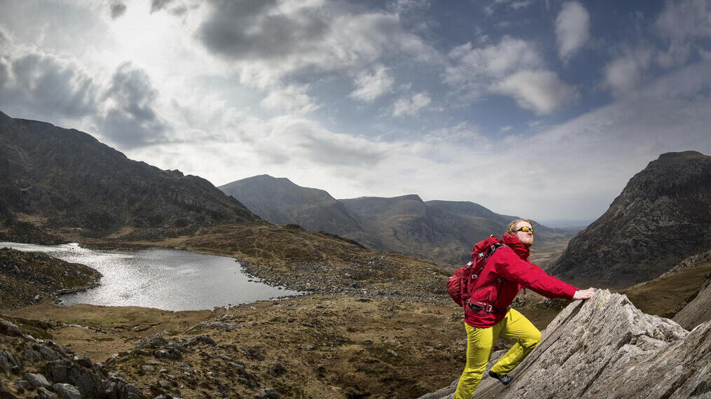 A man climbing a sharp rock formation overlooking a lake