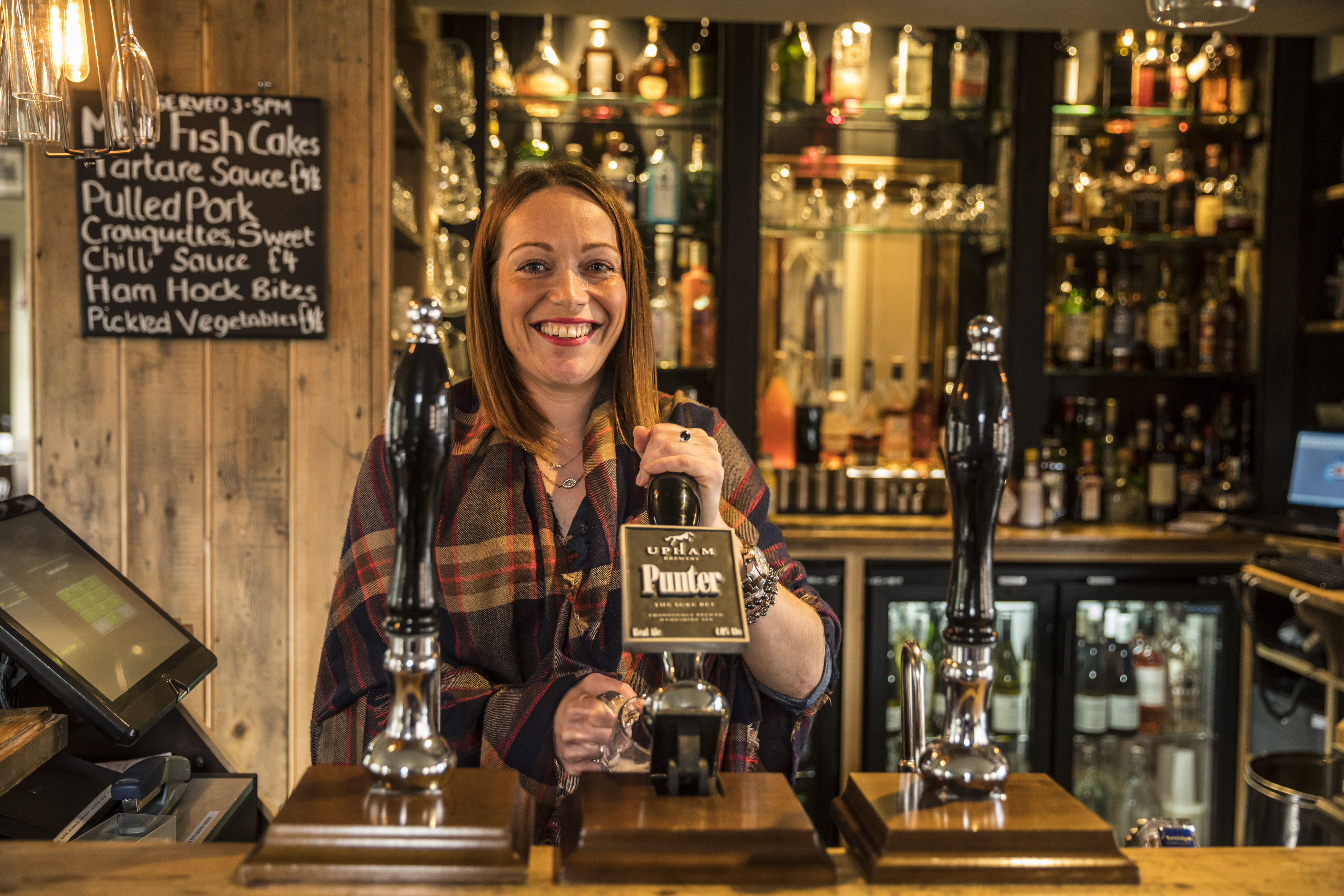 Woman serving drinks behind the bar in a pub