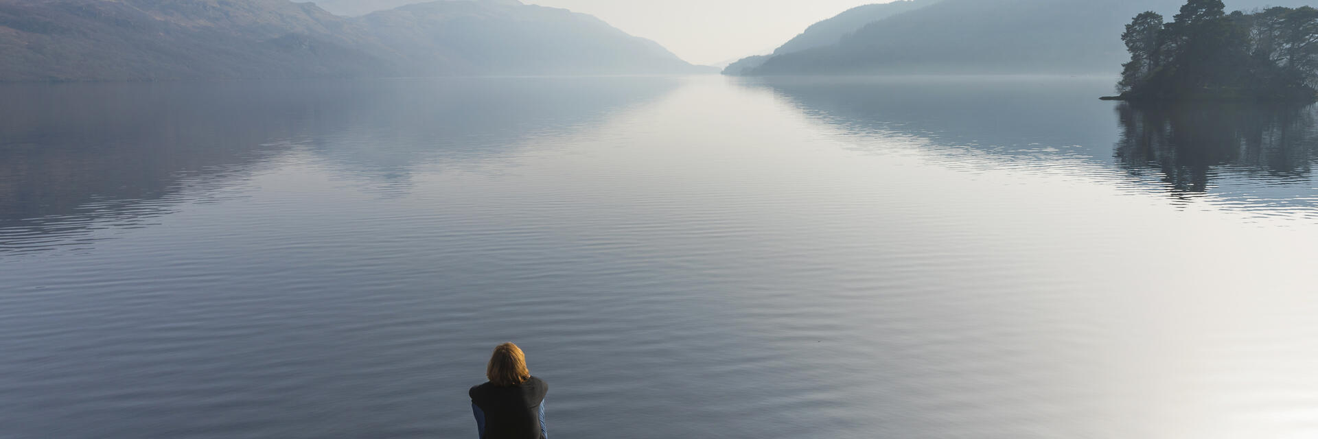 A woman sitting and looking out across Loch Lomond