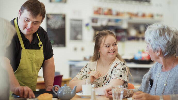 A person with Down's Syndrome serving customers in the cafe