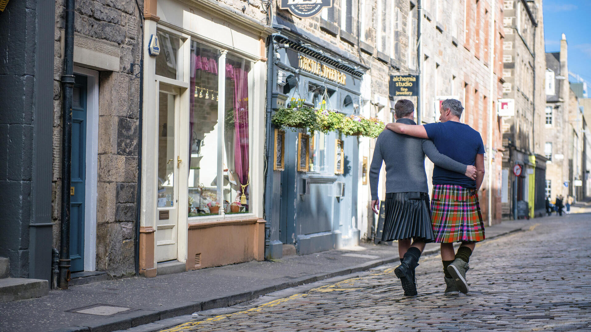 Gleichgeschlechtliches Paar, das Kilts trägt und Arm in Arm geht