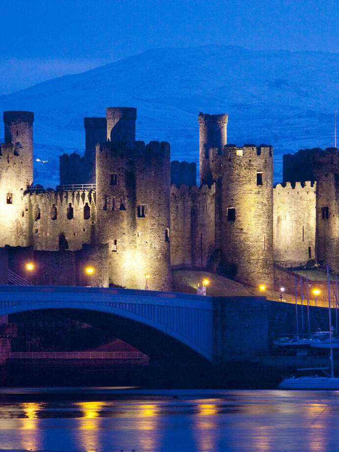 Un castillo iluminado por la noche junto al río