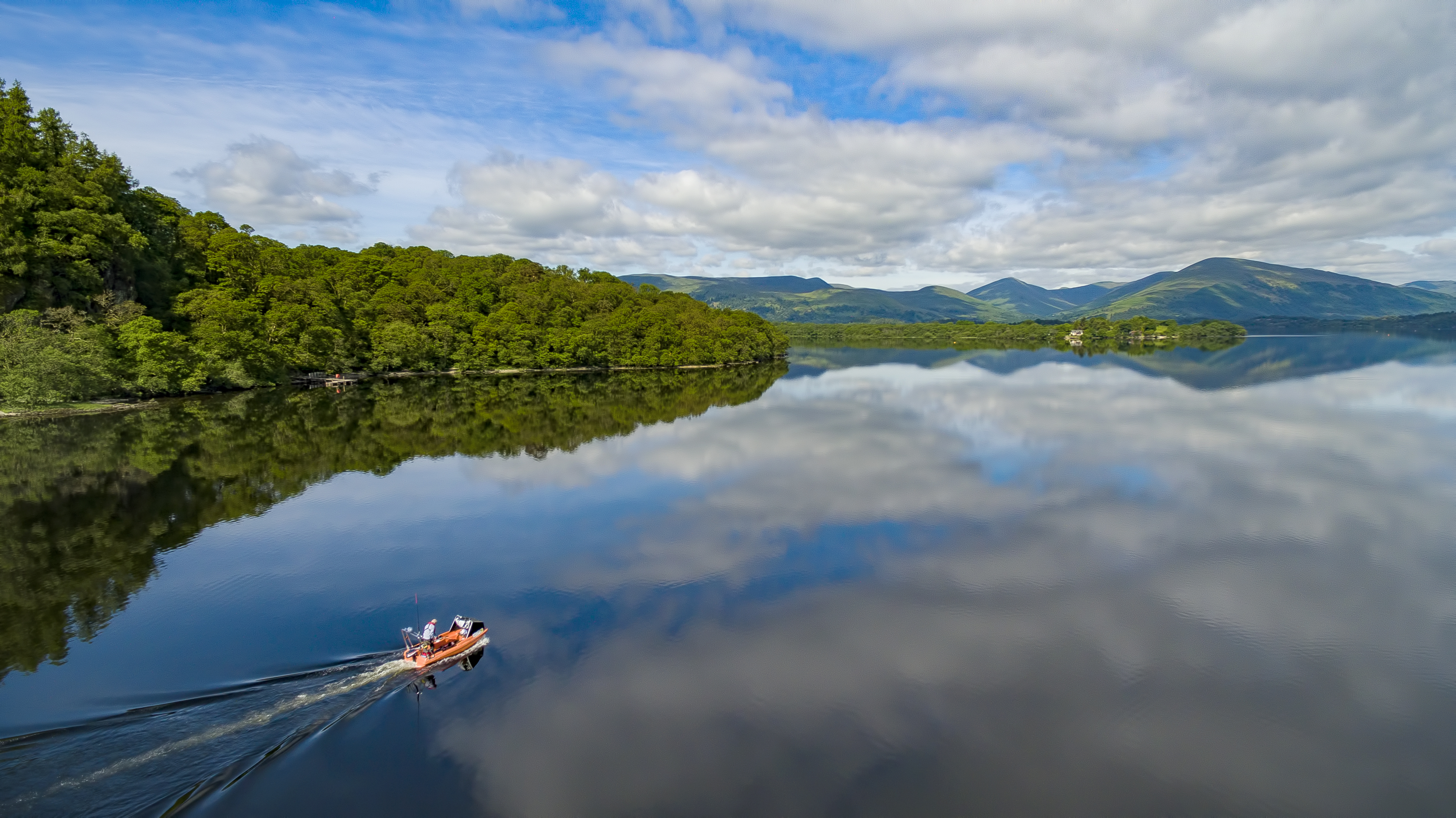 A man powers a motor boat on the waters of Loch Lomond.
