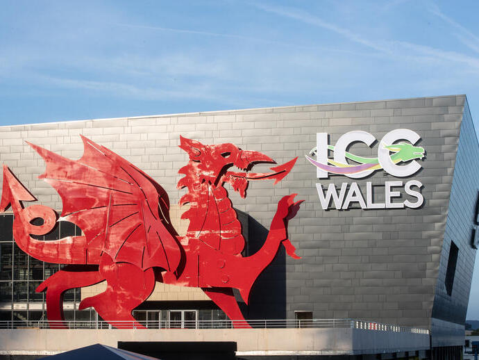 Exterior del centro de convenciones a la luz del día, con un dragón galés rojo y un cartel que dice: ICC Wales.