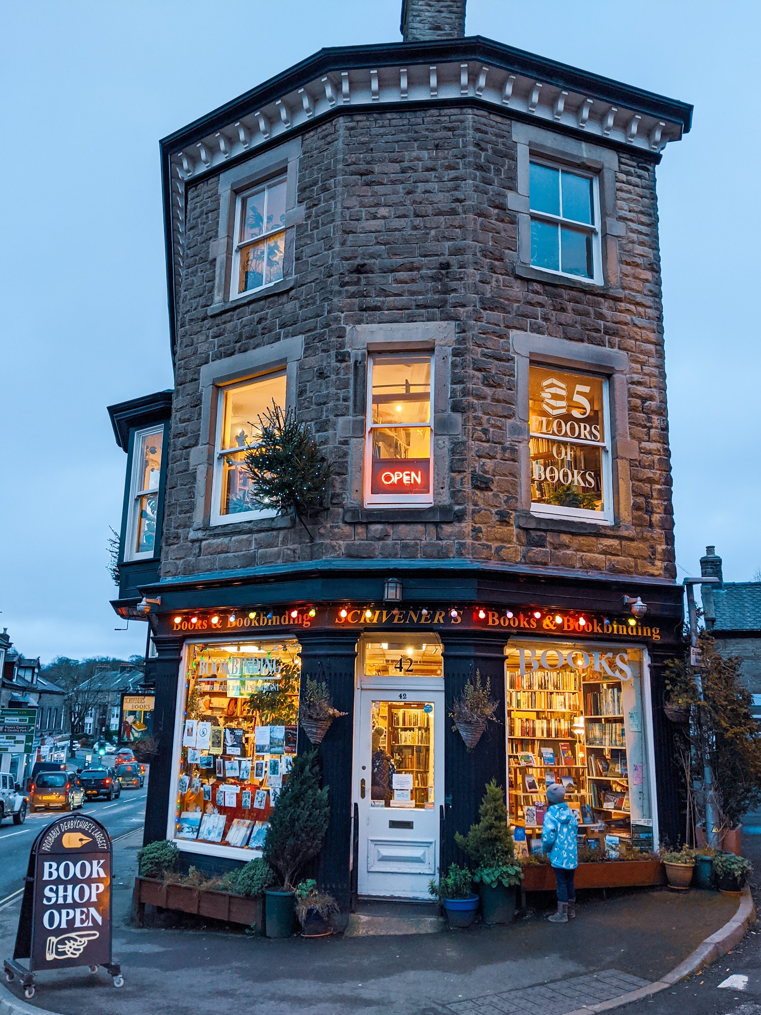 Child looking in the window of a bookshop lit up in the evening light