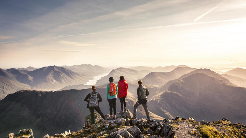 Un grupo de personas de pie en un punto elevado contemplando las vistas de la montaña