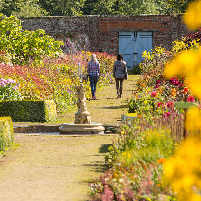 Two female friends walking through a formal garden