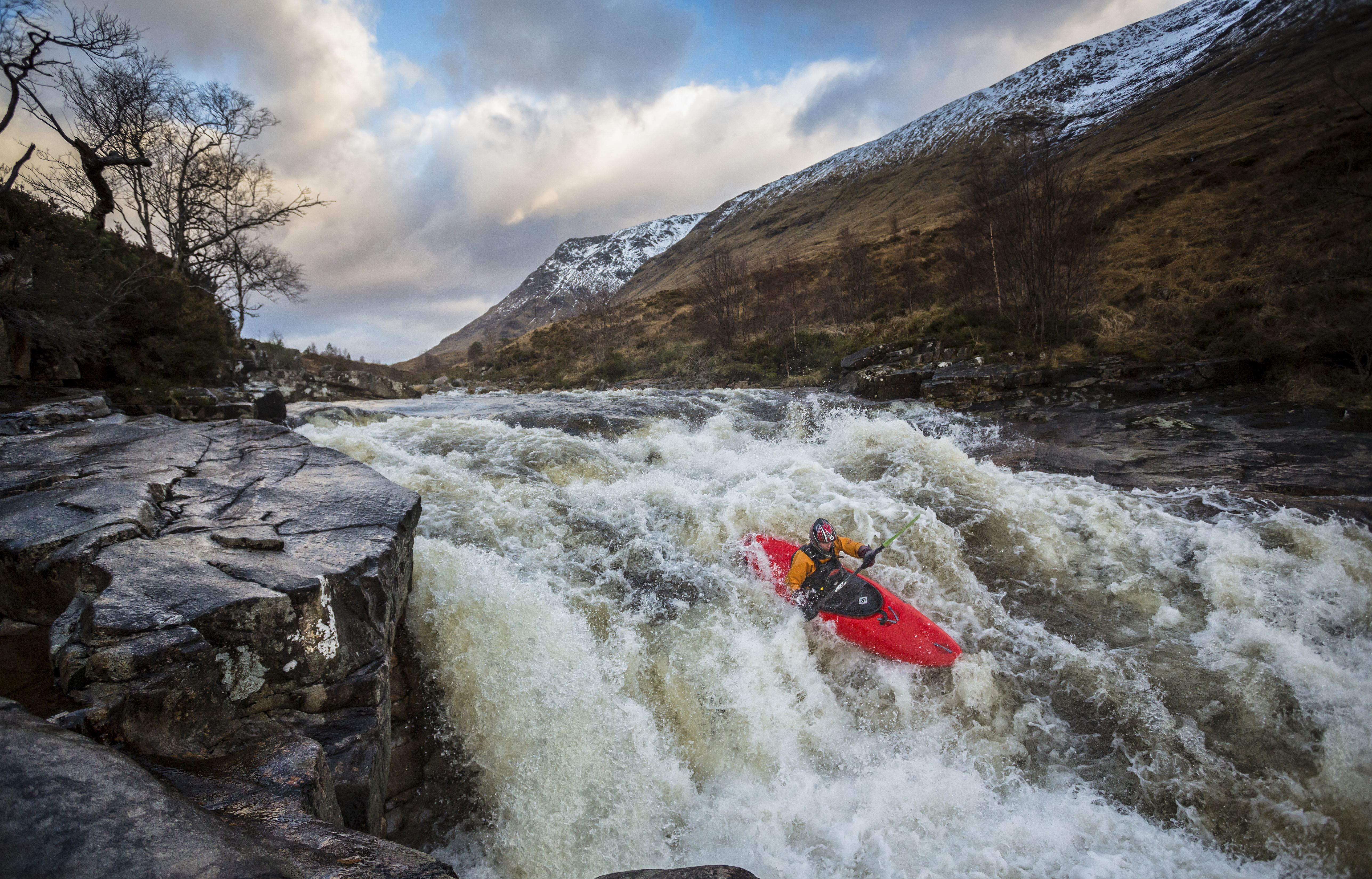 Kayaker, in a red kayak, going over raging rapids