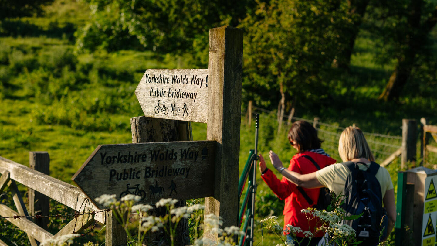 Two women walking in countryside passing sign posts