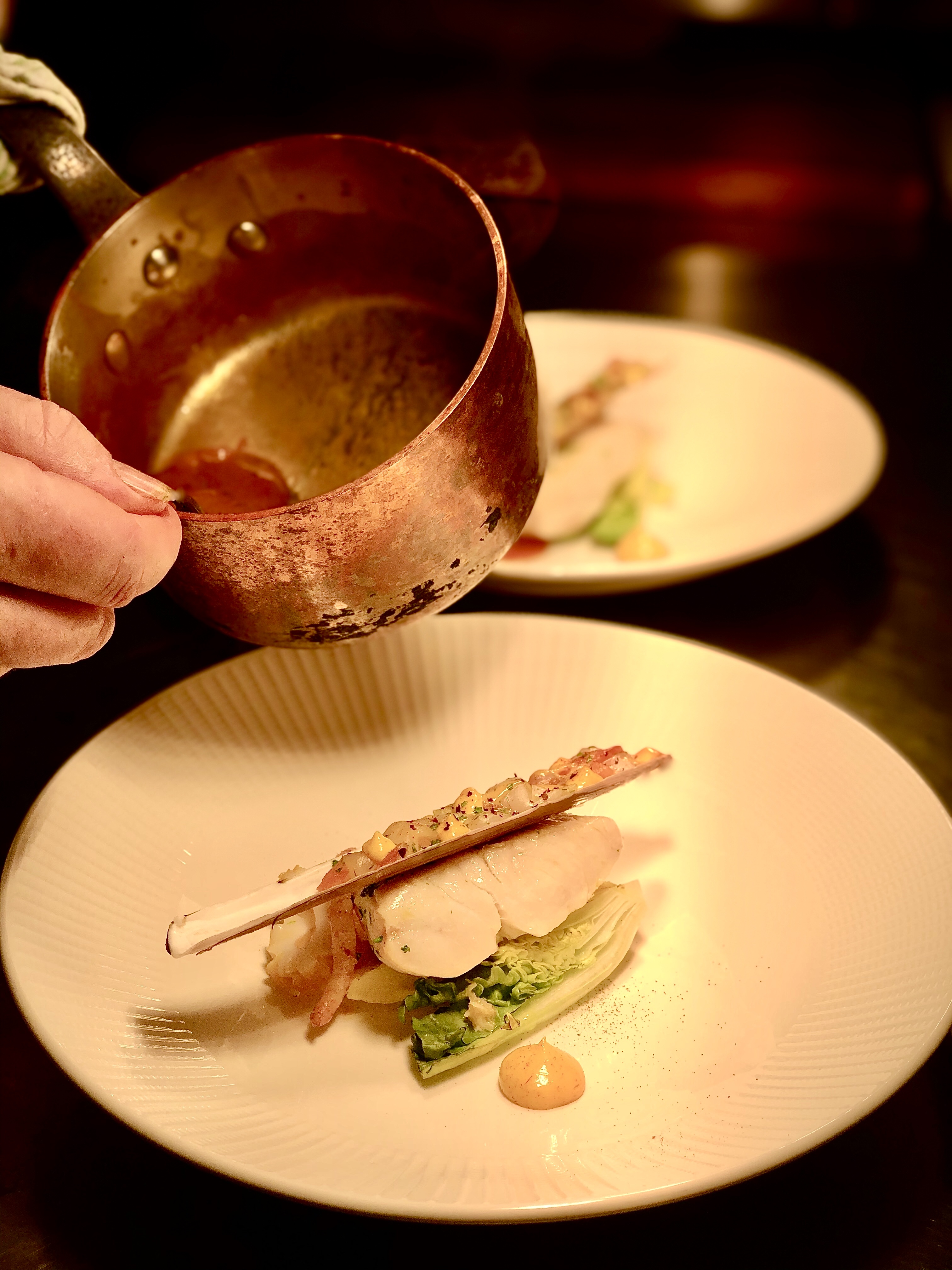 Closeup of someone pouring sauce over a food dish
