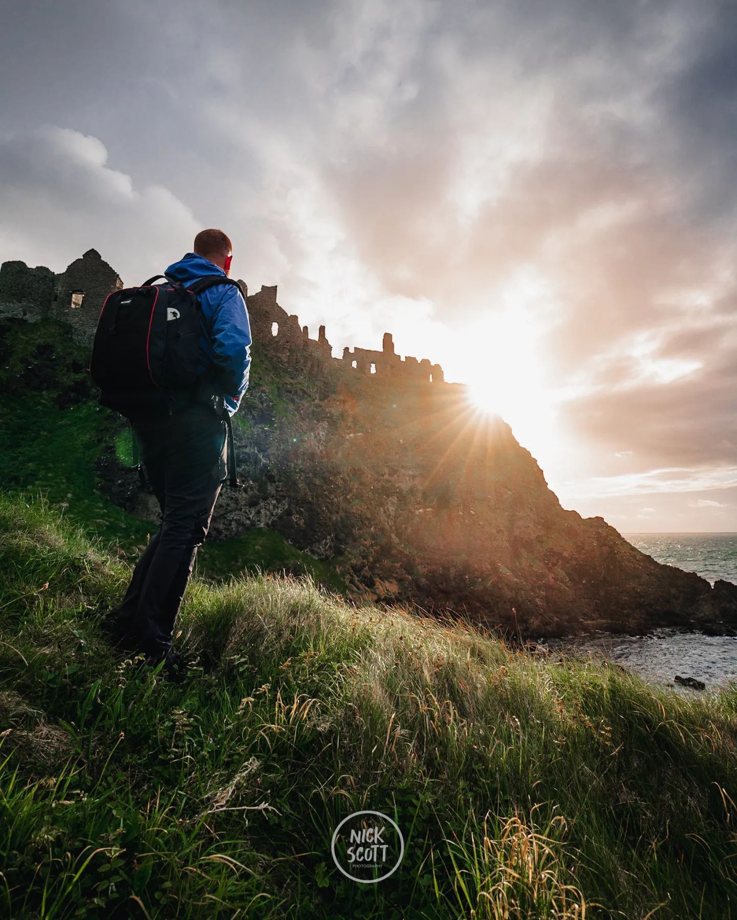 Man walking up hillside as the sun goes down