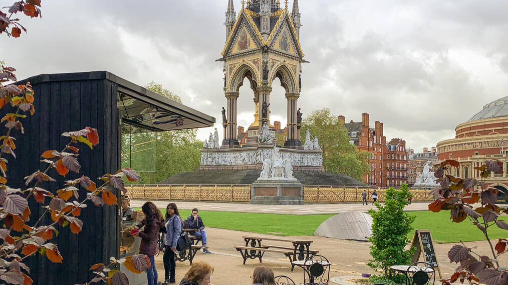 Menschen, die in einem Garten mit Blick auf ein großes Denkmal sitzen.