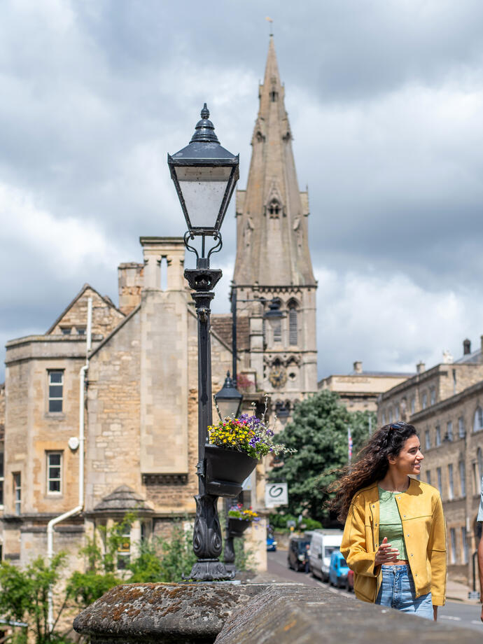A man and a woman walk through a stone built village with a church