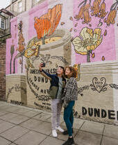 A man and a woman taking a selfie in front of the marmalade mural.