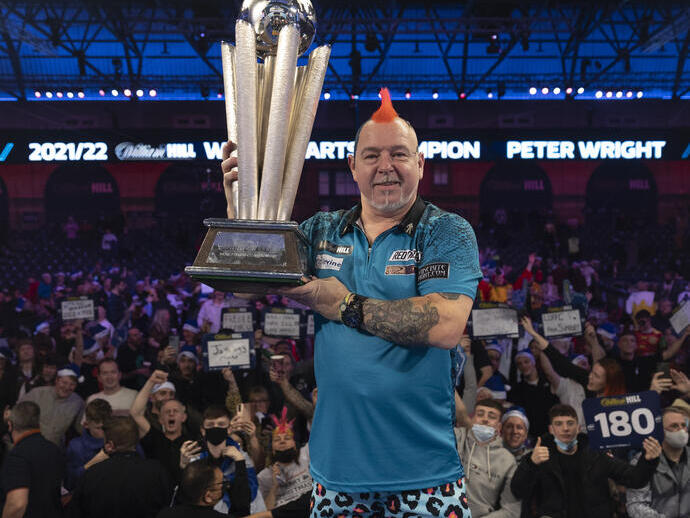 Uomo con in mano un trofeo al World Darts Championship