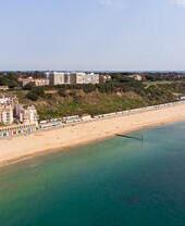 Aerial shot of a sandy beach with colourful beach huts.
