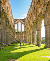 Deux personnes marchant entre les piliers en pierre extérieurs d'un bâtiment en ruines