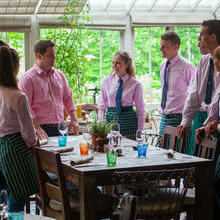 Restaurant staff at a training session dressed in uniform standing around a table at THE PIG in Brockenhurst