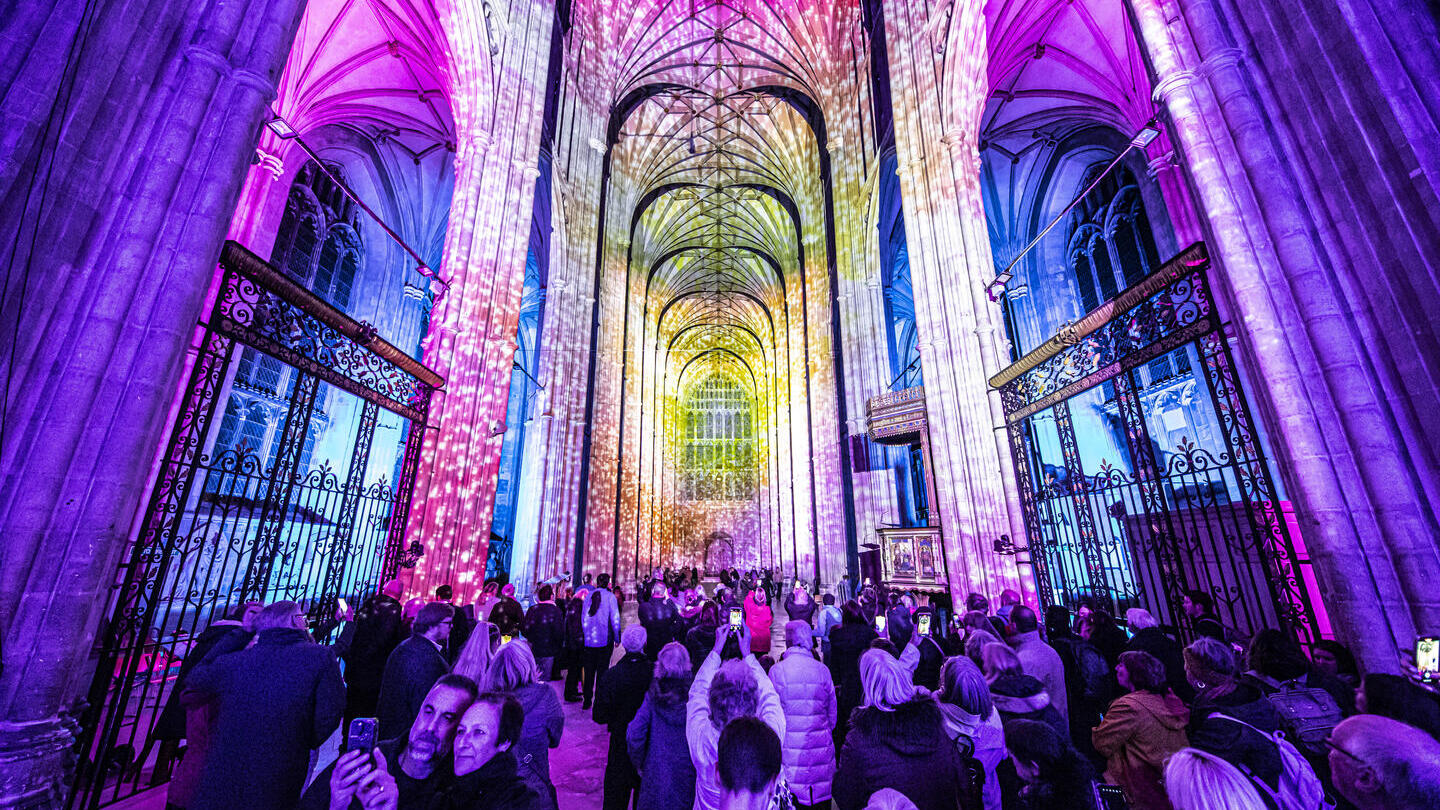 Gruppe von Menschen, die eine Lichtshow in einer Kathedrale betrachten und fotografieren
