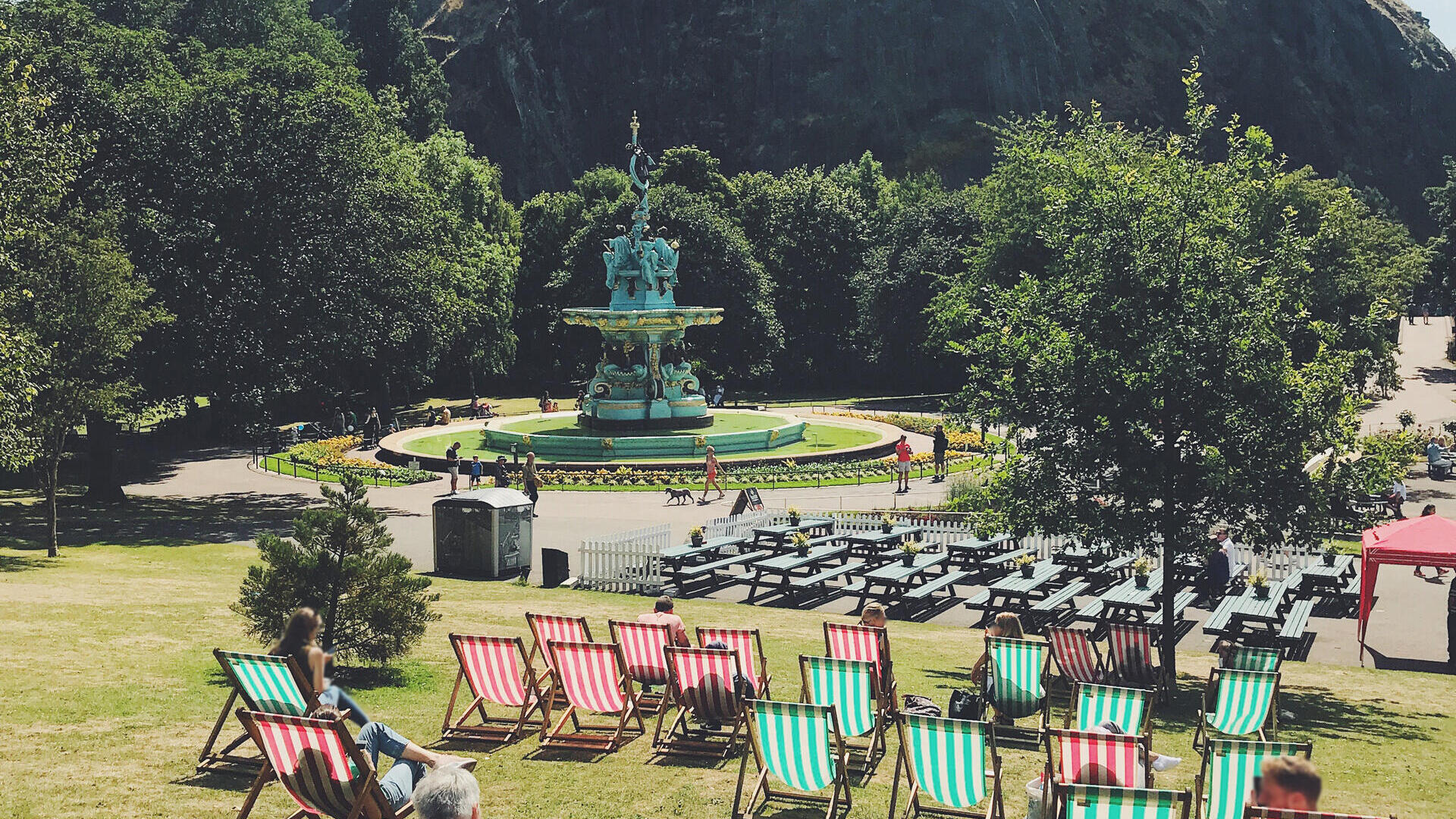Green and red deck chairs laid out on grass in a park in front of a castle