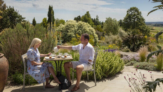 Een man en een vrouw drinken afternoon tea in een tuin in de zomer