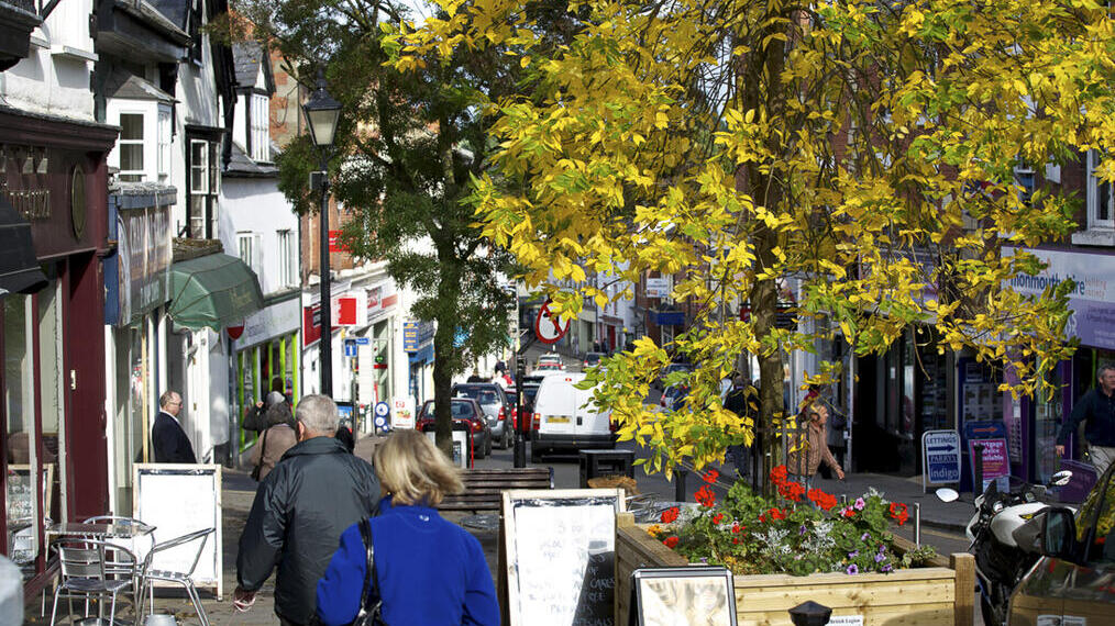 People walking down a hilly shopping street in a small town.