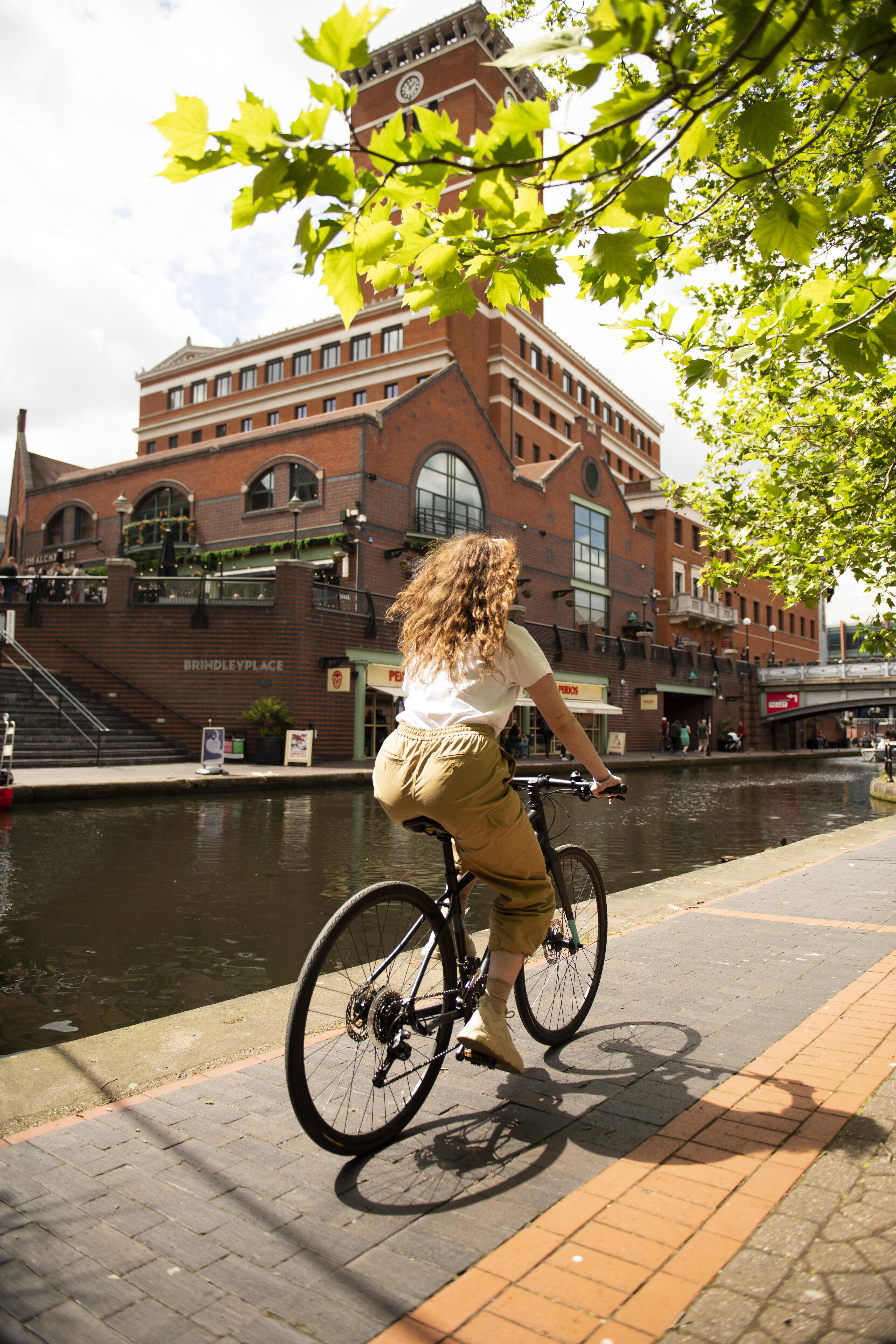 Woman cycling along a canal in a city