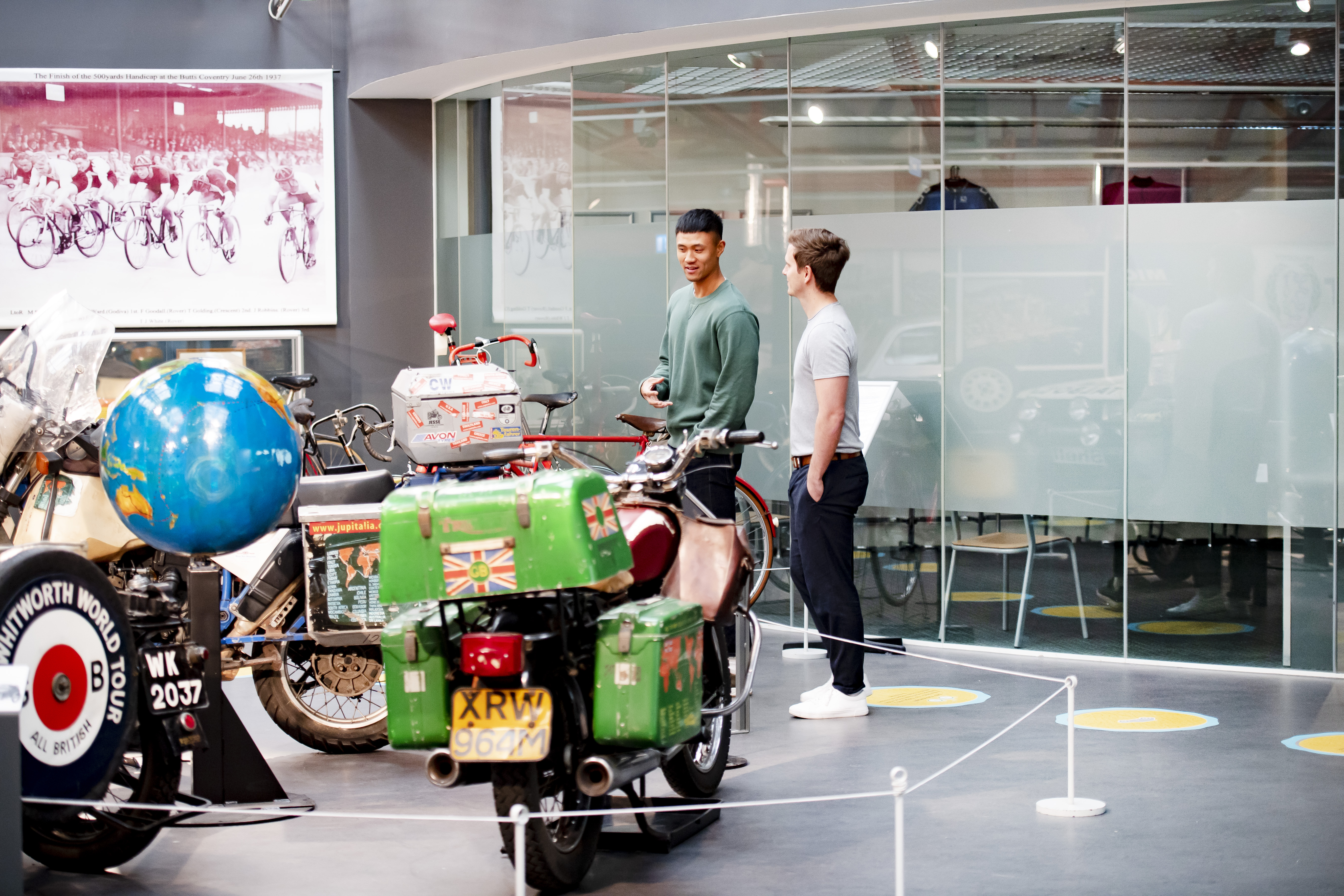Two men looking at an exhibit of motorbikes in a museum.