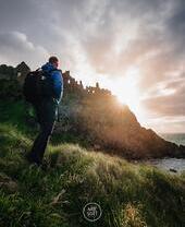 Man walking up hillside as the sun goes down