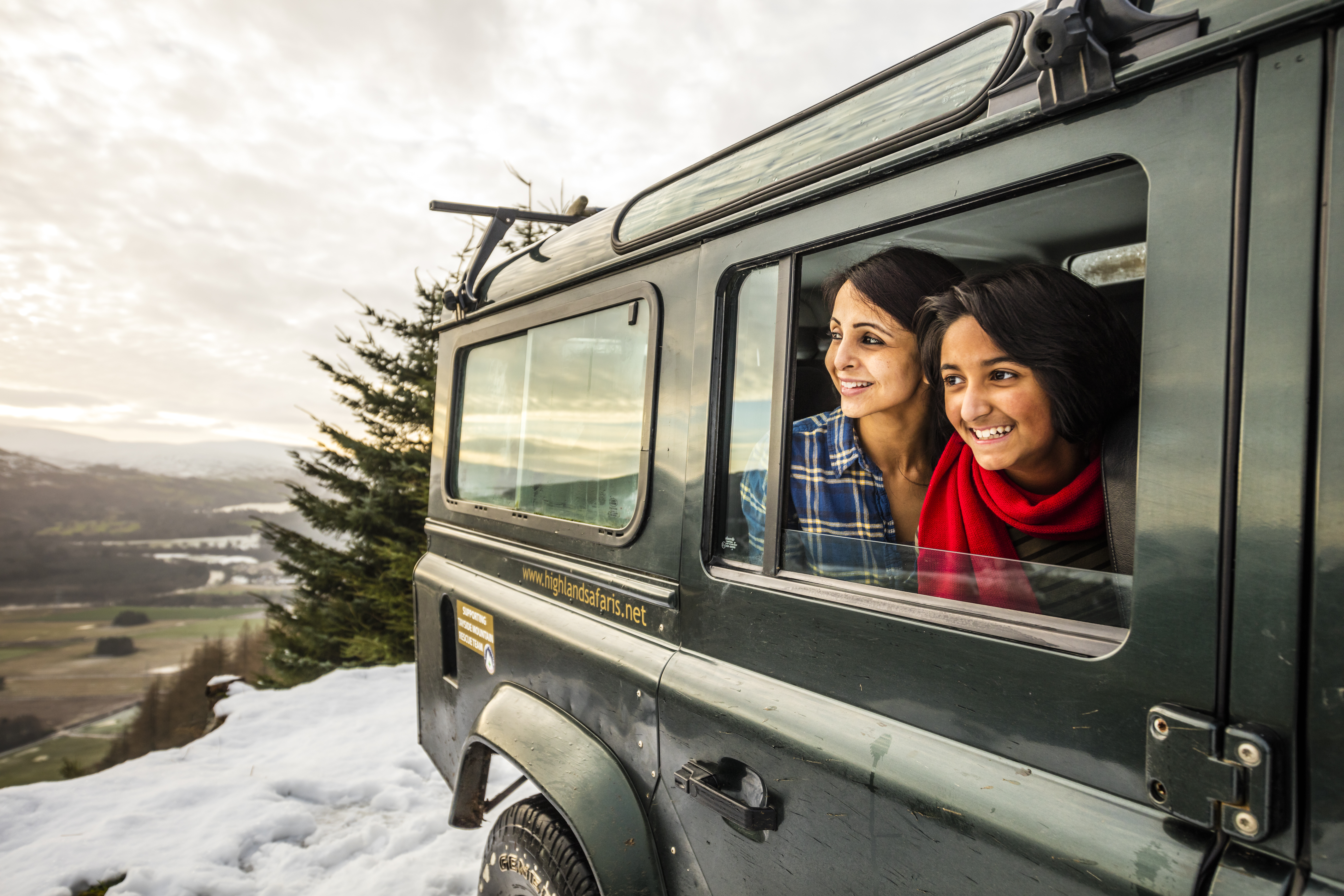 Woman and teenager looking out of a jeep window in the snow