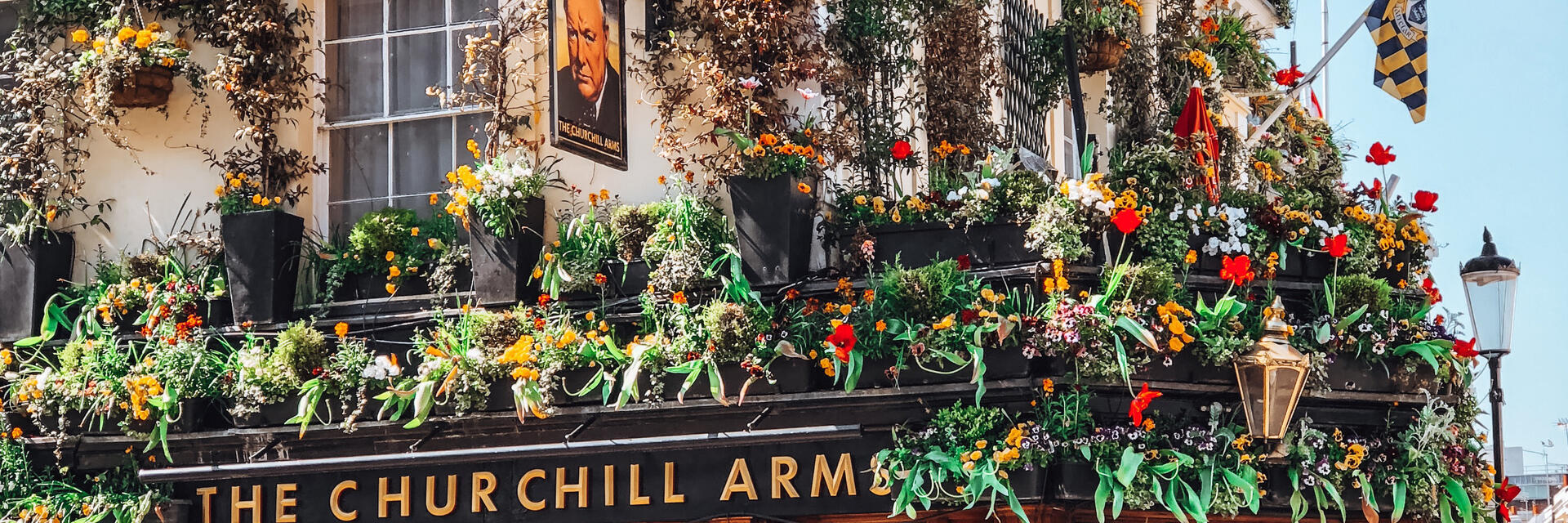 Pub décoré de drapeaux et de paniers suspendus fleuris
