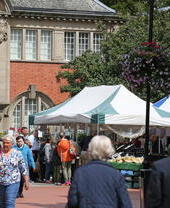 People visiting an outoor produce market near a historic building.