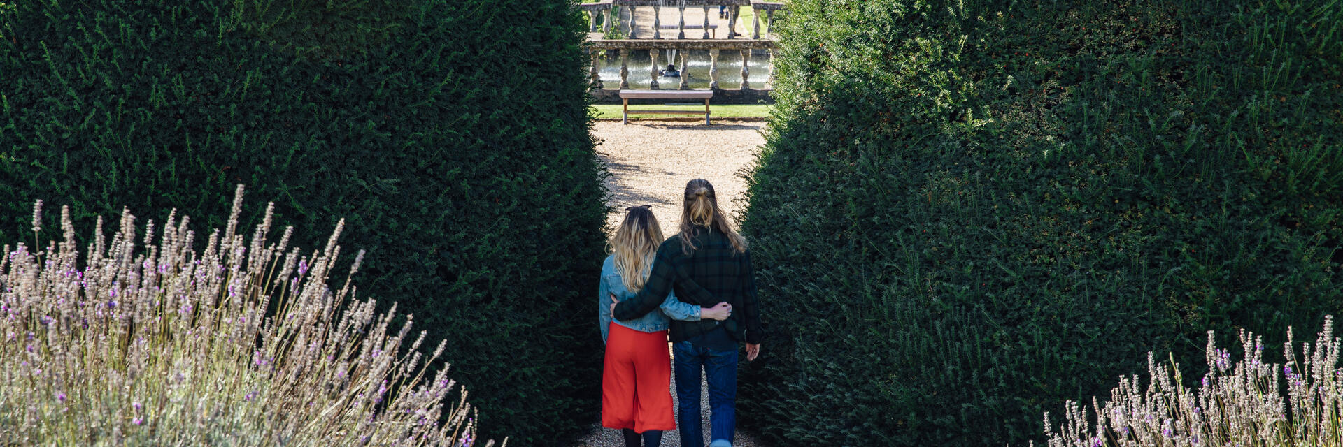 Couple marchant bras dessus bras dessous dans des jardins à la française